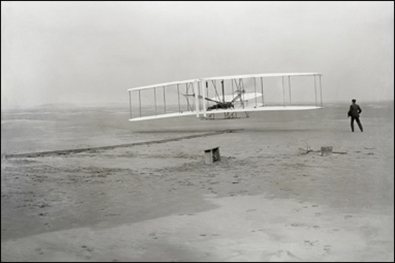 First flight of the Wright Flyer. Orville Wright was piloting; his brother Wilbur was running at wingtip.